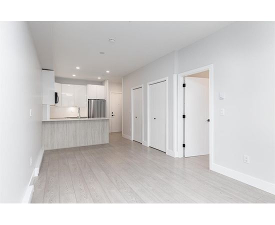 A white kitchen with a refrigerator, microwave, and oven.