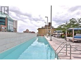 A pool with a metal railing is surrounded by buildings.