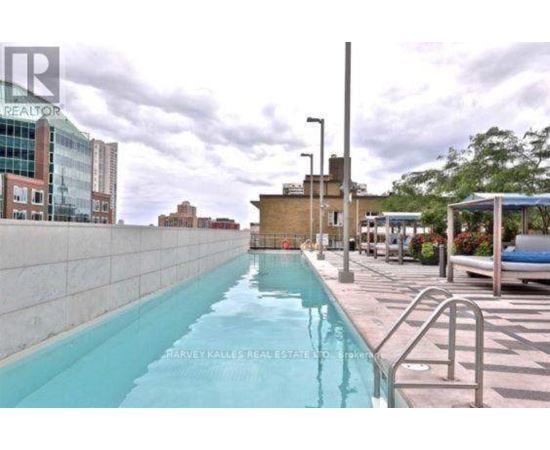 A pool with a metal railing is surrounded by buildings.