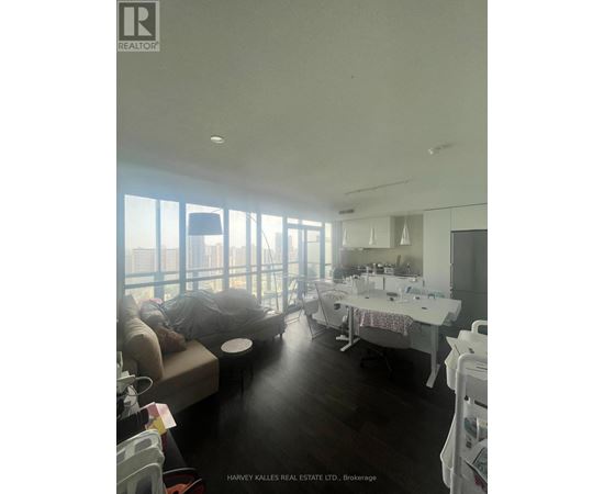 A real estate listing photo of a large open living space with a kitchen area.