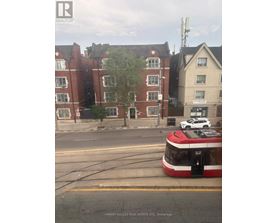 A red and white tram is on the street in front of a building.
