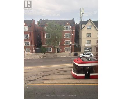 A red and white tram is on the street in front of a building.