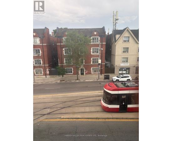 A red and white tram is on the street in front of a building.