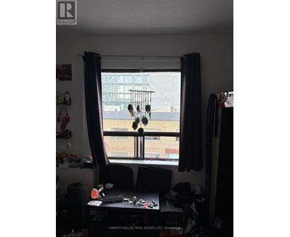 A window with a view of a cityscape is framed by a window seat with a laptop and a pair of headphones hanging from it.