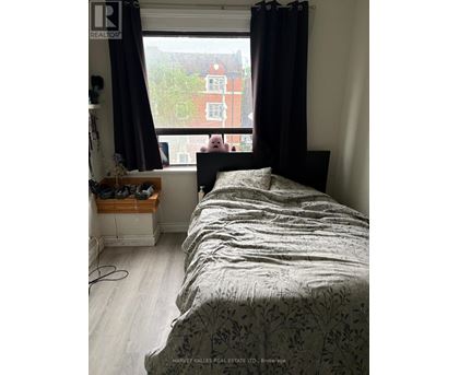 A bedroom with a large bed and a window overlooking a red building.