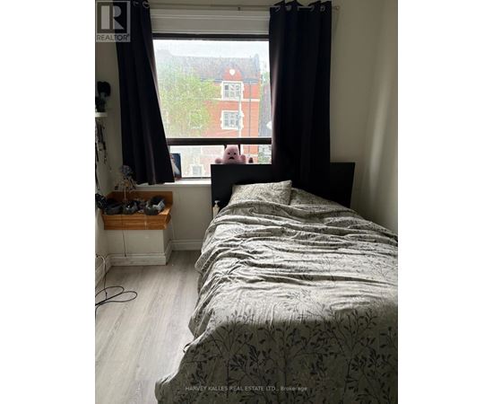 A bedroom with a large bed and a window overlooking a red building.