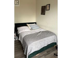 A bed with a white comforter and a black headboard with a green border.