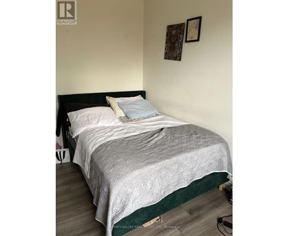 A bed with a white comforter and a black headboard with a green border.