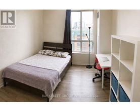 A bedroom with a bed, desk, and chair.