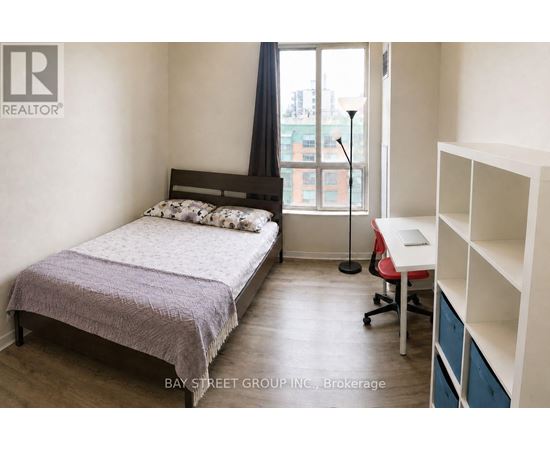 A bedroom with a bed, desk, and chair.