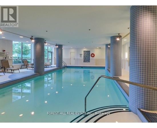 A swimming pool inside a building with a glass wall.