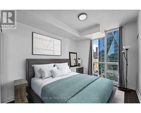 A bedroom with a large bed and a window overlooking a city.