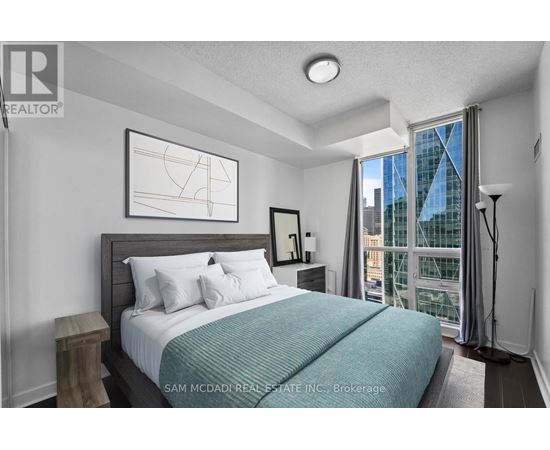 A bedroom with a large bed and a window overlooking a city.