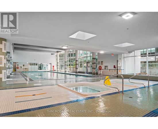 A large indoor swimming pool with a yellow caution sign in the middle.