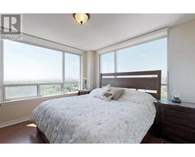 A bedroom with a large bed and a window overlooking the city.