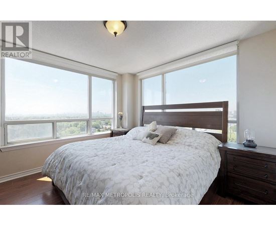 A bedroom with a large bed and a window overlooking the city.