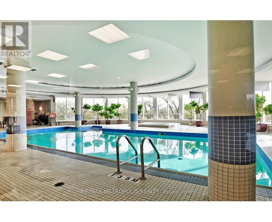 A large indoor swimming pool with a tiled edge and a metal ladder.