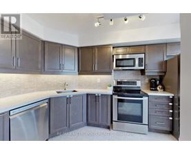 A modern kitchen with dark wood cabinets and stainless steel appliances.