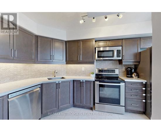 A modern kitchen with dark wood cabinets and stainless steel appliances.
