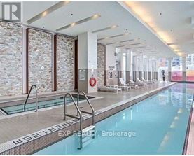 A large indoor swimming pool with a stone wall and a glass divider.