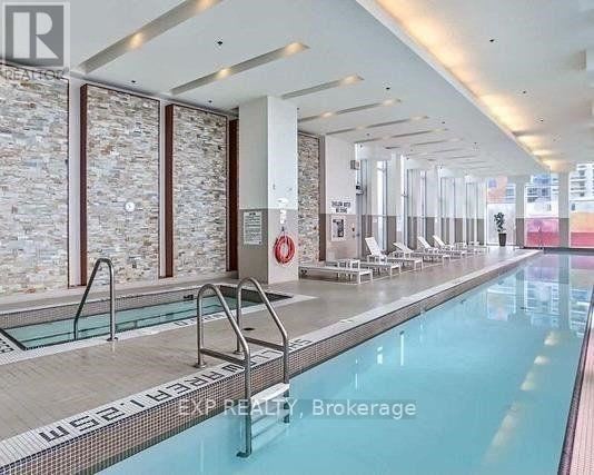 A large indoor swimming pool with a stone wall and a glass divider.