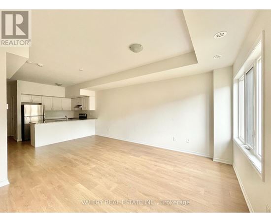 A spacious room with wooden flooring and white walls.