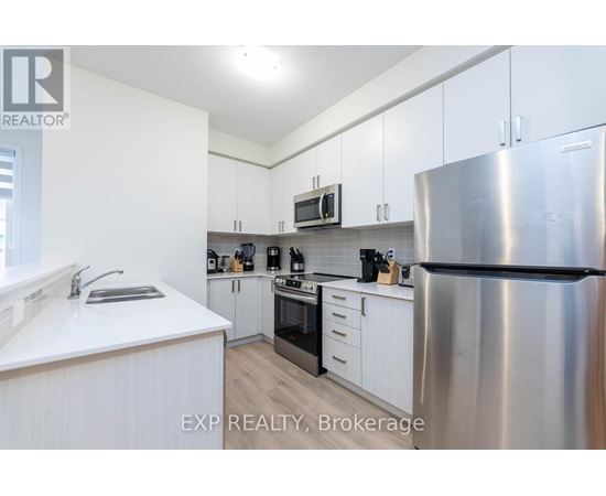 A kitchen with white cabinets and a stainless steel refrigerator.