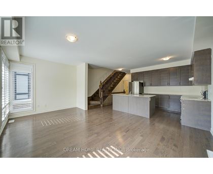 A spacious living room with a staircase leading to the upper floor.