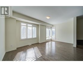A spacious room with wooden floors and a large window.