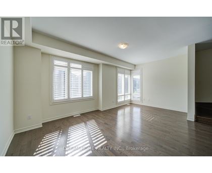 A spacious room with wooden floors and a large window.