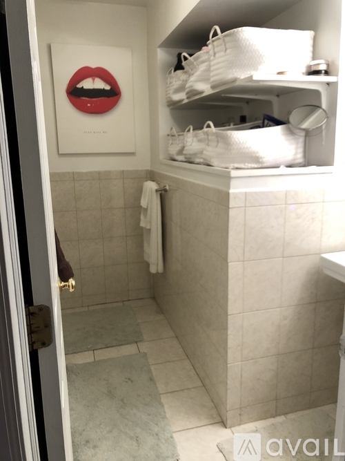 A bathroom with a shelf above the toilet containing white shoes.