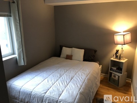 A bedroom with a large bed and a lamp on a side table.