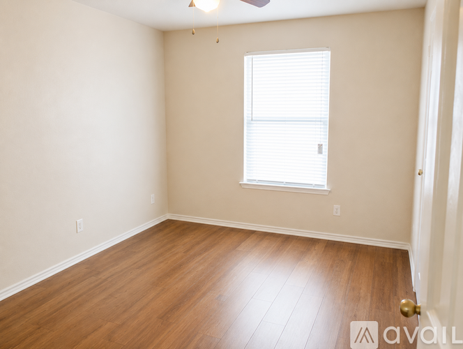 A room with wooden flooring and a window with blinds.