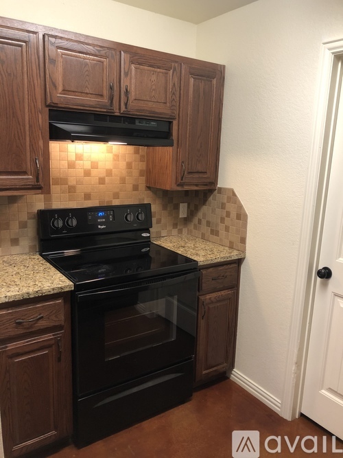 A kitchen with wooden cabinets and a black stove top oven.