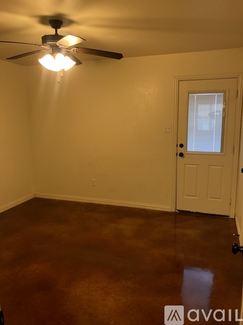 A room with a ceiling fan and brown flooring.