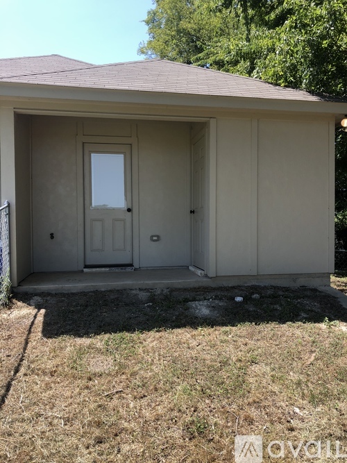 A small beige shed with a brown roof and a white door.