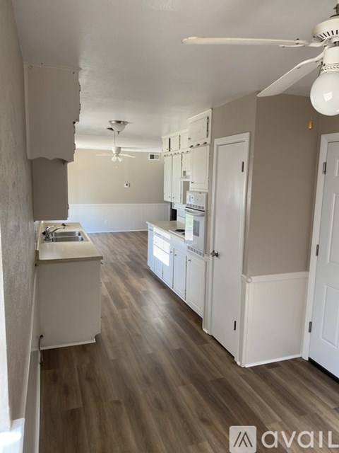 A kitchen with white cabinets and a wooden floor.