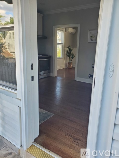 A white door is open to a room with wood flooring.