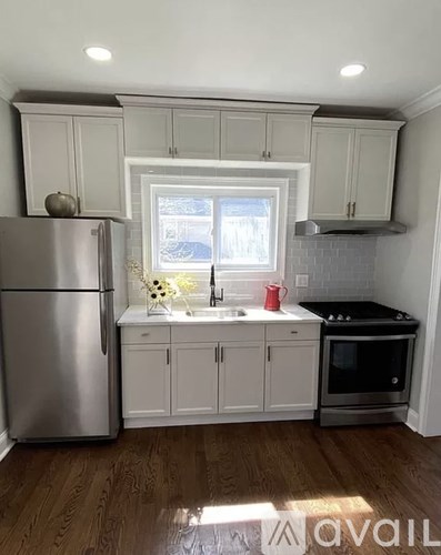 A kitchen with white cabinets and a stainless steel refrigerator.