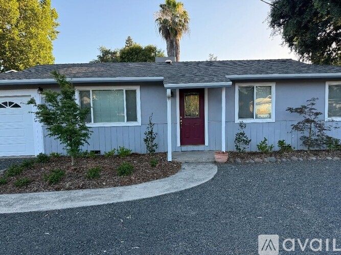 A house with a red door and a gravel driveway.
