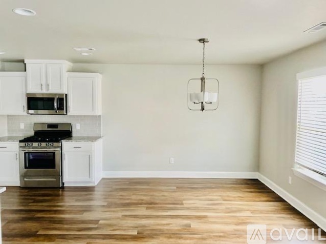 A kitchen with white cabinets and a wooden floor.