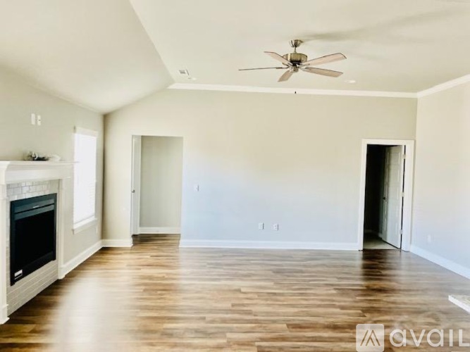 A spacious living room with a fireplace and a ceiling fan.