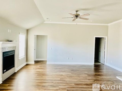 A spacious living room with a fireplace and a ceiling fan.
