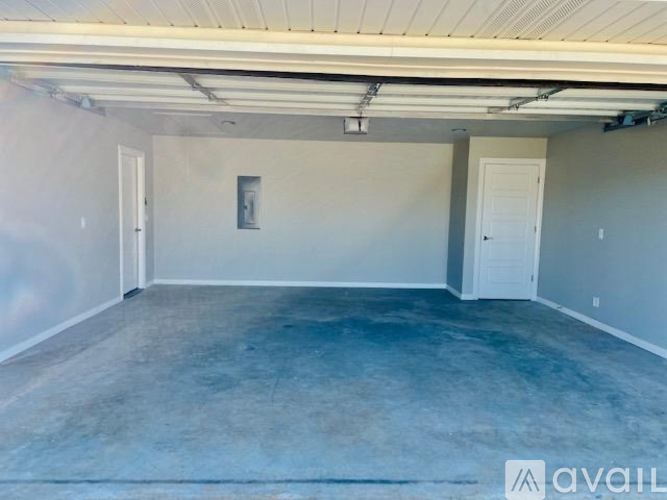 A spacious room with a concrete floor and white walls, with two doors and a window.
