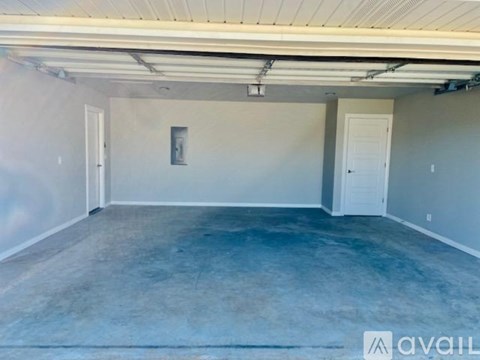 A spacious room with a concrete floor and white walls, with two doors and a window.