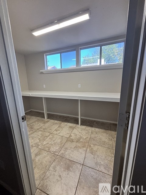 A room with tiled flooring and a window with a view of trees outside.