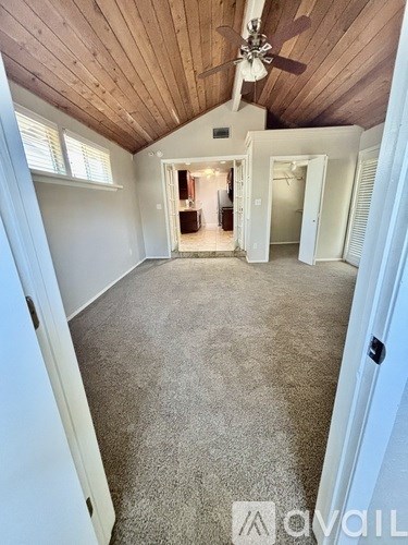 A spacious room with a ceiling fan and carpeted floor.