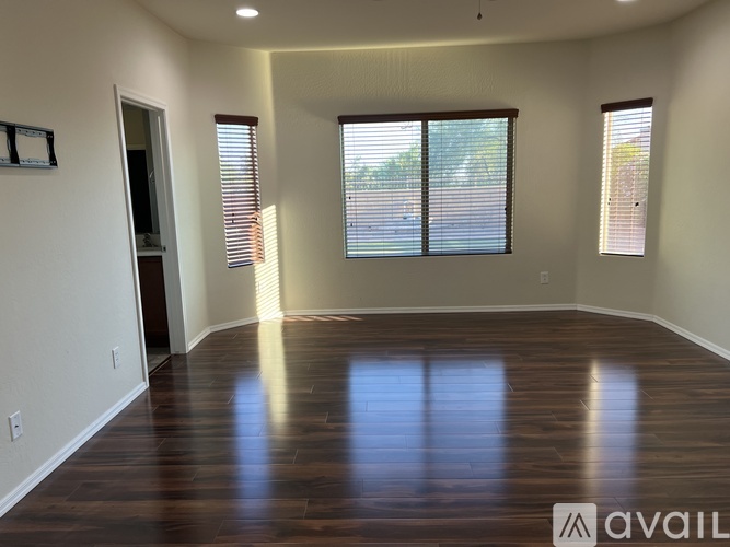 A spacious room with wooden floors and large windows.