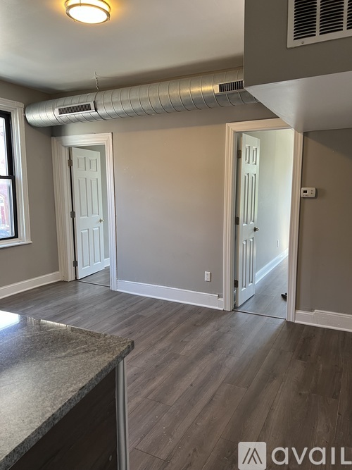 A room with a wooden floor and a window on the left side.