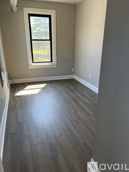 A room with a window and wooden flooring.